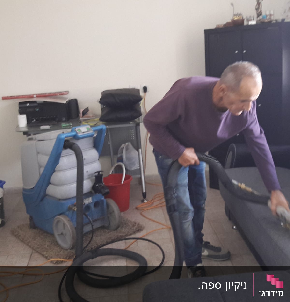 אדם מנקה ספה עם שואב אבק מקצועי